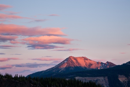 Pink rays of the setting sun light up clouds and the top of Watchman Peak and Watchman lookout at Crater Lake National Park, Oregon.の写真素材