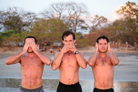 Three very sunburnt young men imitate the classic Hear no Evil, See no Evil, Speak no Evil on the beach in Costa Rica.の写真素材