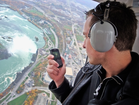 A young man in a helicopter uses his cell phone camera to take a photo of Niagara Falls の写真素材