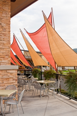 Gold and orange triangle awnings create a shaded area for diners at outdoor patio chairs and tables.の写真素材