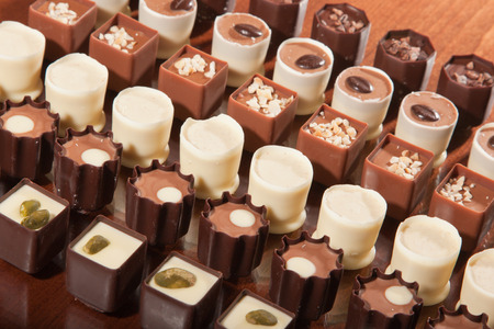 Rows of artisan chocolate truffles lined up by type on a wooden table.の写真素材