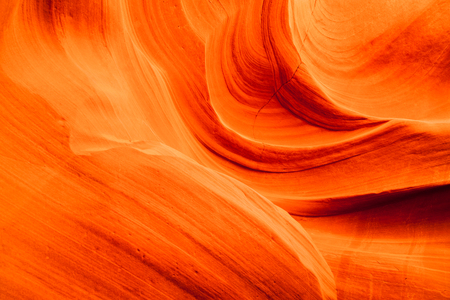 Background of vibrant orange swirling sandstone rocks inside of Upper Antelope Canyon in Page, Arizona.の写真素材