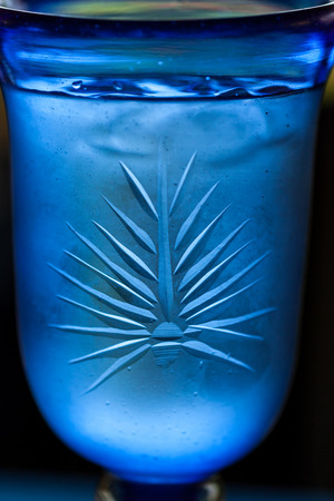 An interesting pattern on a blue chalice filled with ice water and condensation forming on the outside.の写真素材