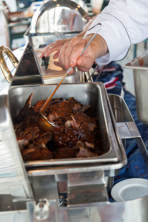 A chef ladling huckleberry barbecue sauce over tender cooked pork ribs at a celebration.の写真素材