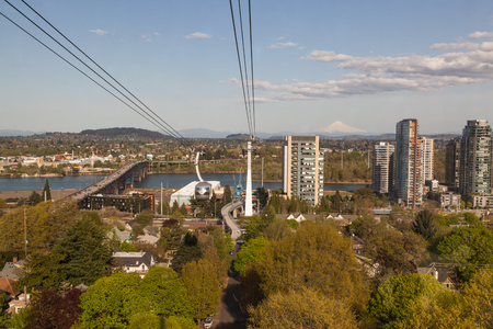 PORTLAND, OREGON - April 14, 2014:  A tram car view of city buildings, Ross Island Bridge crossing the Willamette River and a distant Mount Hood in Portland, OR on April 14, 2014.のeditorial素材