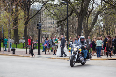 MADISON, WISCONSIN - May 10, 2014: People on a crowded street corner as a motorcycle turns the corner in Capital Square  in Madison, WI on May 10, 2014.のeditorial素材