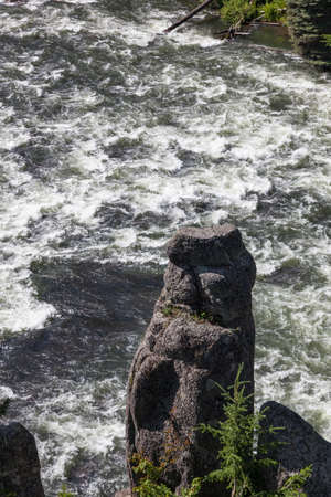 A rock pillar stick up next to a wild section ofHenrys Fork of the Snake River near Upper Mesa Falls located along the Mesa Falls Scenic Byway in Idaho.の写真素材