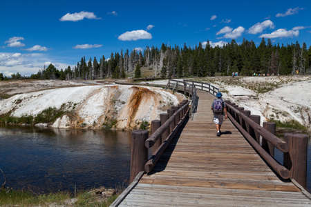 Yellowstone National Park, Wyoming / USA - July 22, 2014:  A man walking across a wooden bridge spanning the Firehose River on a sunny summer day at Yellowstone National Park in Wyoming.のeditorial素材