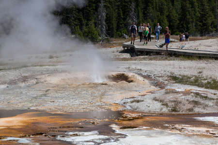 Yellowstone National Park, Wyoming / USA - July 22, 2014:  A group of tourists walk on a wooden boardwalk above geothermal land with active geysers at Yellowstone National Park in Wyoming.のeditorial素材