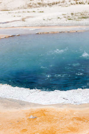 Deep blue boiling water inside of Crested Pool with a white rim at Yellowstone Natural Park.の写真素材