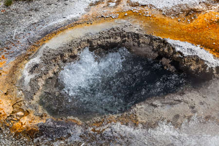 An eye shaped opening in the ground filled with boiling water from underground geothermal activity at Yellowstone National Park, Wyoming.の写真素材