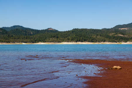 Low water levels reveal red clay and rocks at Lost Creak Lake near Prospect, Oregon located in the Cascade Mountain Range.の写真素材