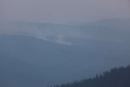 Thick smoke from the 790 Fire in the Cascade Mountains blocks the layers of thickly forested ridges in the late afternoon light.の写真素材