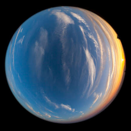 Layers of smoke from a nearby wildfire give an orange glow to the setting sun over the Cascade Mountains with wispy white clouds in the deep blue sky. Fish-Eye effect.の写真素材