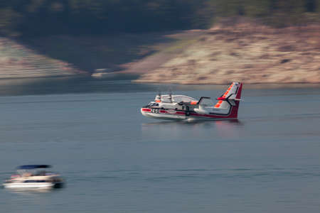 Lost Creek Lake near Prospect,  Oregon / USA - September 7, 2014:  A small fire fighting plane prepares to scoop water from the lake to fight the 790 Fire near Prospect at Lost Creek Lake, Oregon. Panning effect.のeditorial素材