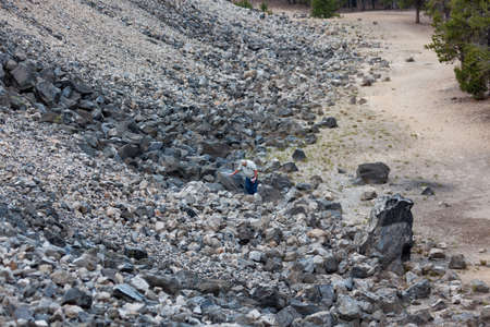 Newberry National Monument, Oregon / USA - August 17, 2014:  An older man looks at rocks on the edge of an enormous obsidian flow in Newberry National Volcanic Monument, Oregon.のeditorial素材