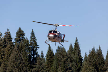 Prospect,  Oregon / USA - September 9, 2014:  A fire fighting helicopter pilot looks out his window at a long rope attached to a bucket as he takes off to to fight the 790 Fire near Prospect, Oregon.のeditorial素材