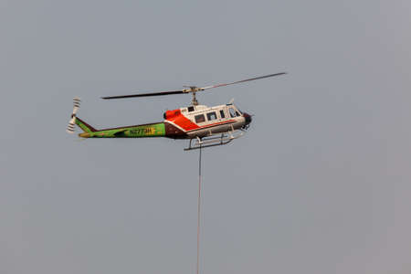 Prospect,  Oregon / USA - September 13, 2014:  A fire fighting helicopter takes off in a smoke filled sky from Prospect State Airport with a hanging rope and bucket to help put out the 790 Fire near Prospect, Oregon.のeditorial素材