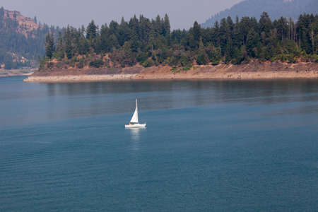 Lost Creek Lake near Prospect,  Oregon / USA - September 7, 2014:  A small white sailboat skims the calm surface at Lost Creek Lake near Prospect, Oregon.のeditorial素材