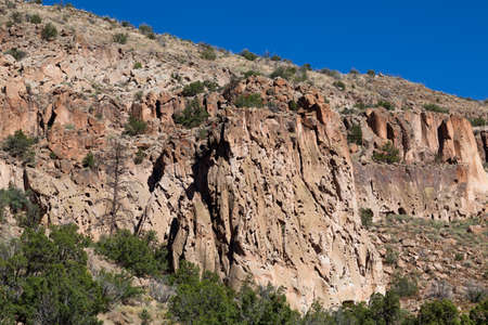 Large rock cliffs inside of Frijoles Canyon that was home to the ancestral Pueblo people who carved cave dwellings at the base in Bandelier National Monument, New Mexico.の写真素材