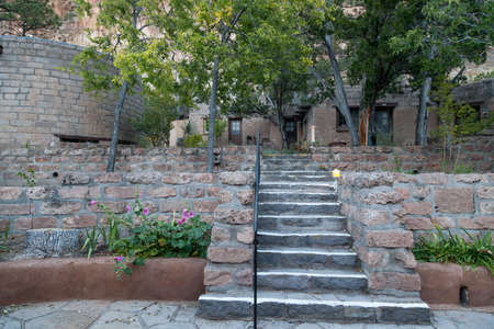 Modern buildings built in the Pueblo style serve as a visitors center and gift shop in Bandelier National Monument with tall eroded sandstone walls in the distance.の写真素材