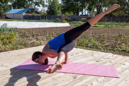 A yoga instructor holds an intricate pose of flexibility and balance at an outdoor afternoon yoga class at a farm.の写真素材