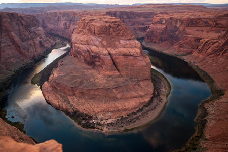 Looking down from the high cliffs at Horseshoe Bend view point to boats and people on the shore across the Colorado River setting up camp for the night.の写真素材
