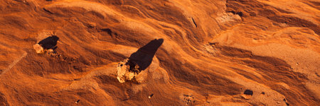 Late afternoon sunshine creating long shadows on small pebbles resting upon eroding sandstone rocks in the American Southwest.の写真素材