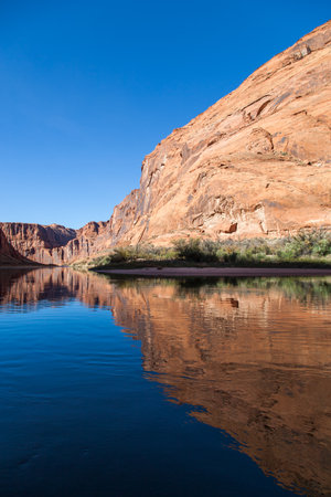 Light, shadow, and calm water make a perfect combination to reflect the sandstone walls of Glen Canyon onto the Colorado River in an artistic view.の写真素材