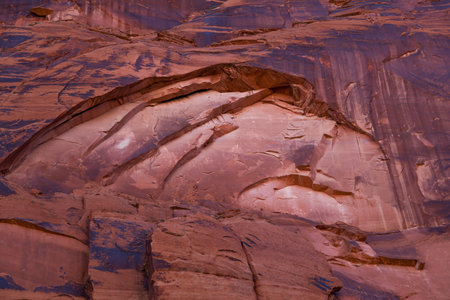 Eroding sandstone canyon walls creating an arch pattern with newer bright sandstone exposed in the arch, and dark patina on the older sandstone surrounding it.の写真素材