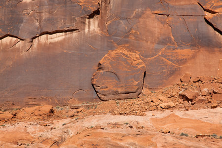 A large chunk of sandstone wall that has broken off and slid down to rest sitting upright against the ancient patina of Glen Canyon.の写真素材