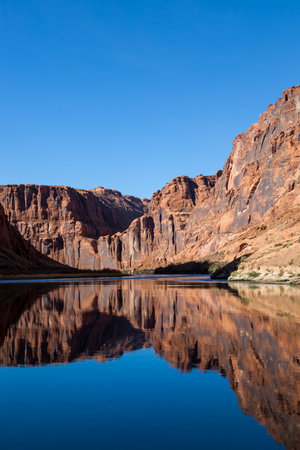 Light, shadow, and calm water make a perfect combination to reflect the sandstone walls of Glen Canyon onto the Colorado River in an artistic view.の写真素材