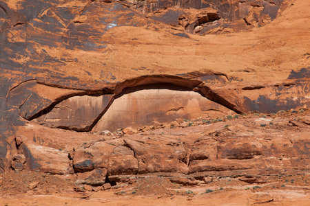 Eroding sandstone canyon walls creating an arch pattern with newer bright sandstone exposed in the arch, and dark patina on the older sandstone surrounding it.の写真素材