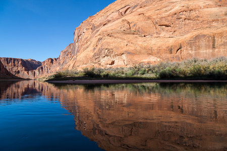 Light, shadow, and calm water make a perfect combination to reflect the sandstone walls of Glen Canyon onto the Colorado River in an artistic view.の写真素材