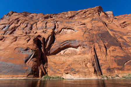 Eroding sandstone canyon walls creating two arch patterns with newer bright sandstone exposed in the arch, and dark patina on the older sandstone surrounding it.の写真素材