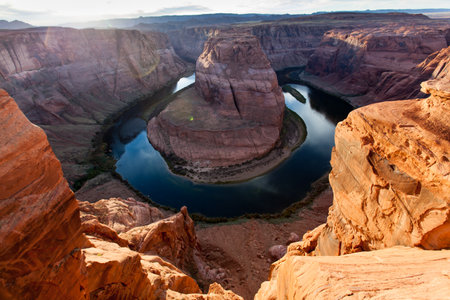 Giant orange sandstone boulders create a frame to view the famous Horseshoe Bend in the Colorado River which runs through Glen Canyon in Arizona.の写真素材
