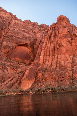Ancient sandstone walls tower over the Colorado River in Glen Canyon showing interesting geology of years past.の写真素材
