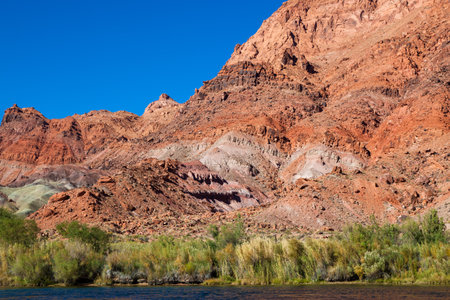 Ancient sandstone walls tower over the Colorado River in Glen Canyon showing interesting geology of years past.の写真素材