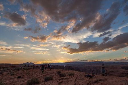Horseshoe Bend, Arizona / USA - October 25, 2014:  Several tourists dot the landscape at Horseshoe Bend near Page, Arizona to look over the cliff edge at sunset to see the Colorado River below.のeditorial素材