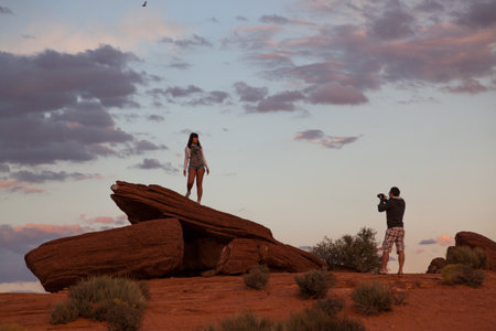 Horseshoe Bend, Arizona / USA - October 25, 2014:  A man takes a picture of a woman standing on an orange sandstone rock formation with fading afternoon light at Horseshoe Bend near Page, Arizona.のeditorial素材