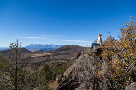 A woman sitting on a high rock and enjoying the view of the valley and surrounding mountains near Zion National Park, Utah.の写真素材