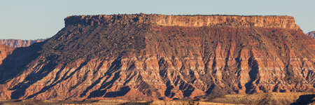 A high plateau of eroding sandstone with a dark square on the left and white and red stripes to the side and below that loosely resembles the American Flag.の写真素材