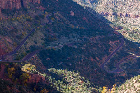The curvy and steep road that winds through Zion National Park as it goes from a high elevation to the valley floor with cars that look like toys compared to the sheer size.の写真素材
