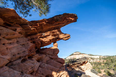 Iron capped sandstone that has eroded over thousands of years to form a small window in the rock with a small piece holding a large upper slab in Zion National Park, Utah.の写真素材