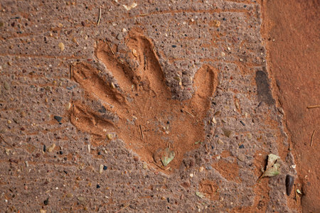 The impression of a hand into a concrete walkway near Angel's Landing in Zion National Park that has filled with orange sand over time.の写真素材