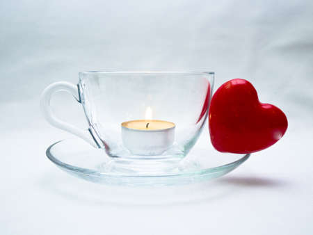 Still life wiht glass cup and red heart and candleの写真素材