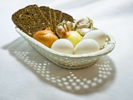 Cheese, eggs, bulb and garlic in a wum white basketの写真素材