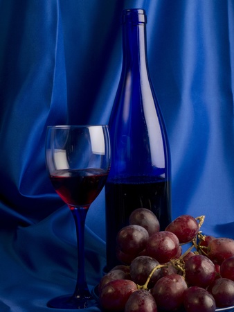 Red wine and grapes on a blue backgroundの写真素材