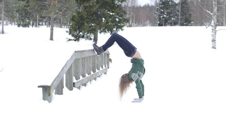Girl performs gymnastic exercise in the fresh air in the winter