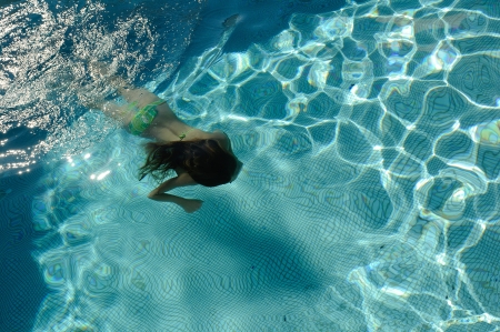 Girl swimming in a pool under waterの写真素材